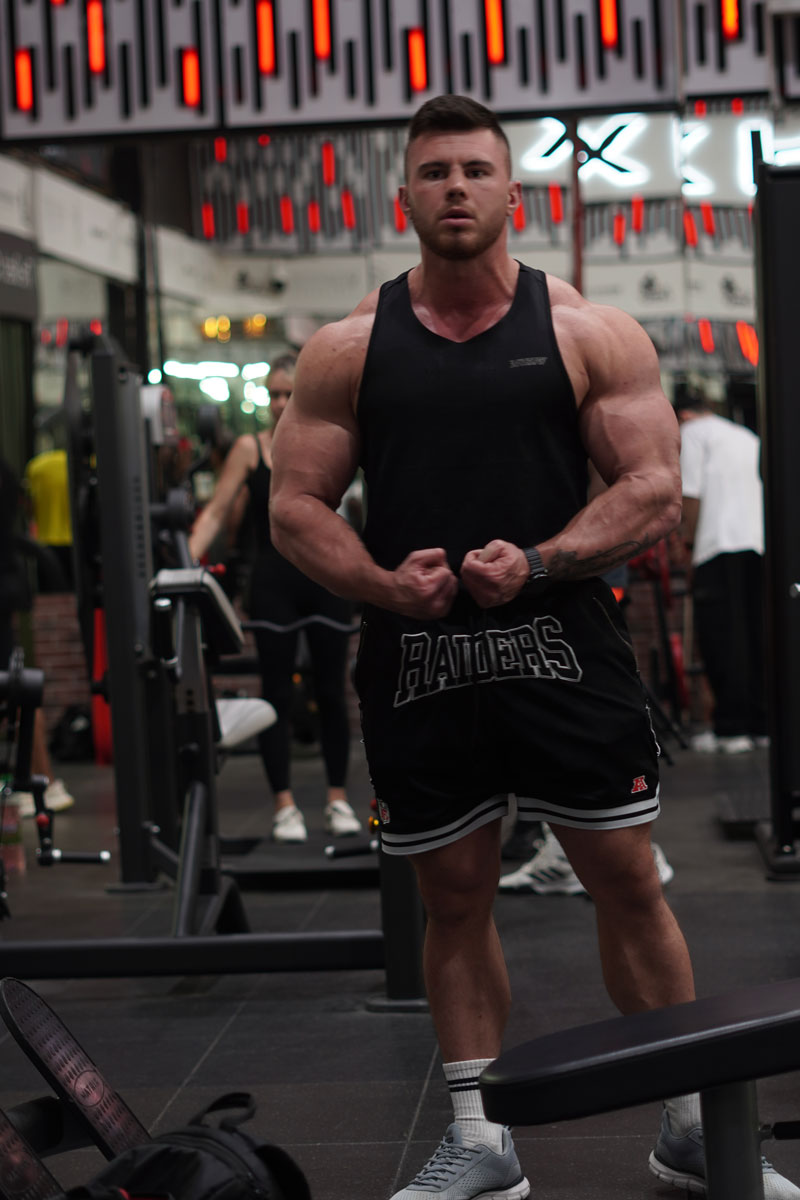 The coach is posing while showing his muscles.